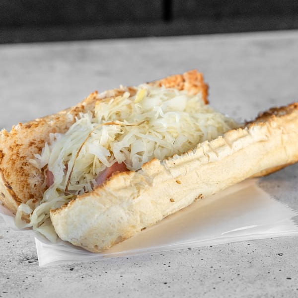 A close-up of a hot dog in a bun, topped with a generous serving of sauerkraut.