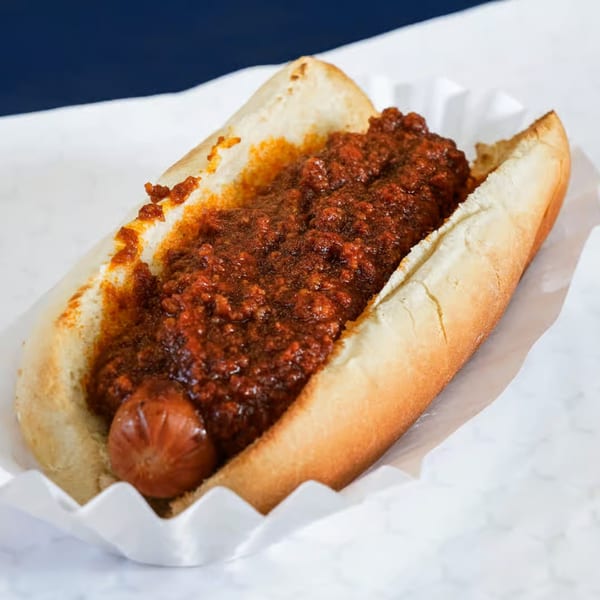 A chili dog with a hot dog and thick chili in a bun, served in a paper tray.