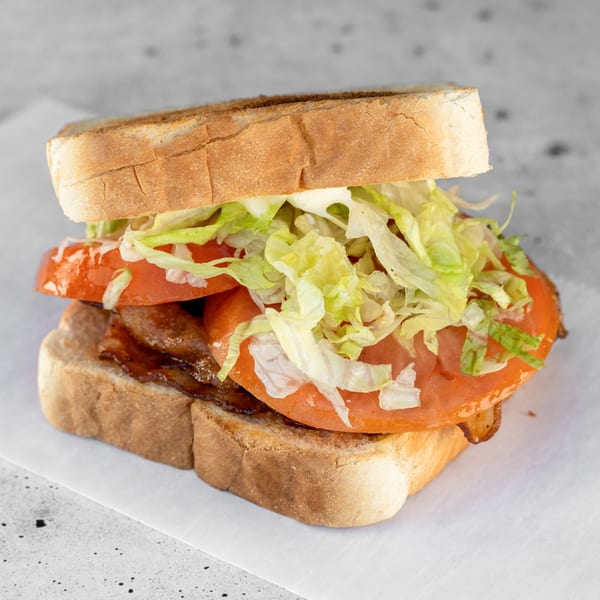 A delicious BLT sandwich with crispy bacon, fresh tomatoes, and shredded lettuce on toasted bread.