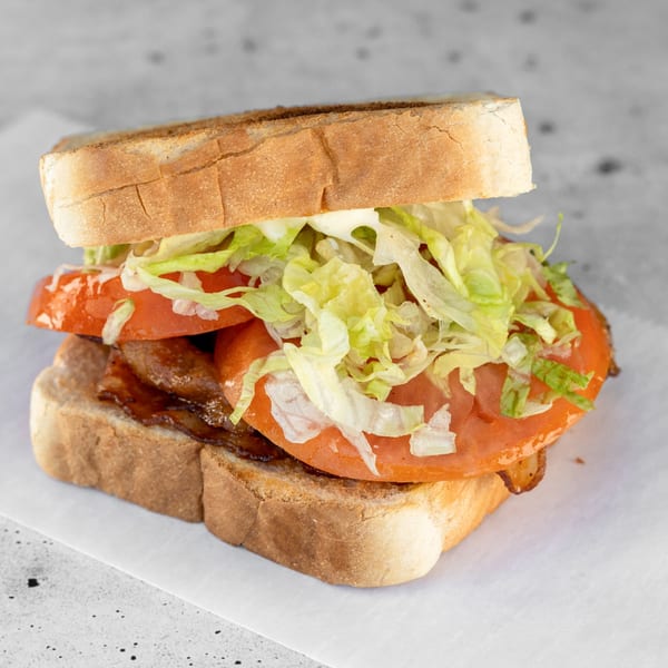 A BLT sandwich with crispy bacon, sliced tomatoes, and shredded lettuce on toasted white bread.