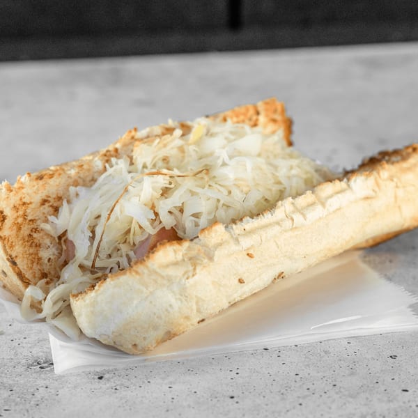 A close-up of a hot dog in a bun, topped with a generous amount of sauerkraut.