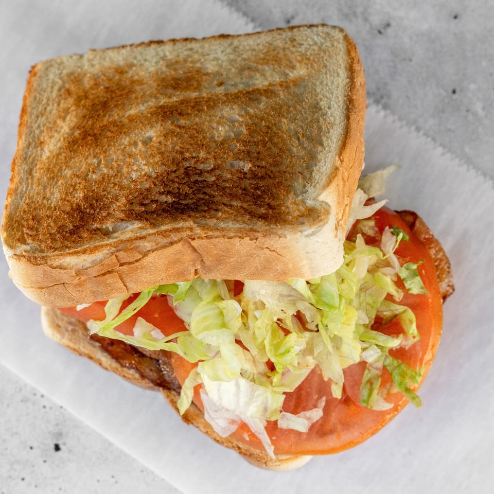 Top-down view of a sandwich with toasted bread, lettuce, tomato, and a creamy sauce.