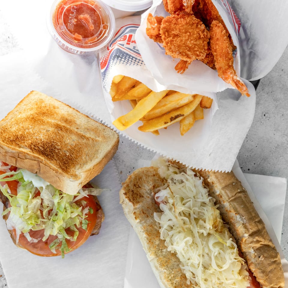 Top-down view of fried shrimp, french fries, a sandwich, and a hot dog with sauerkraut.
